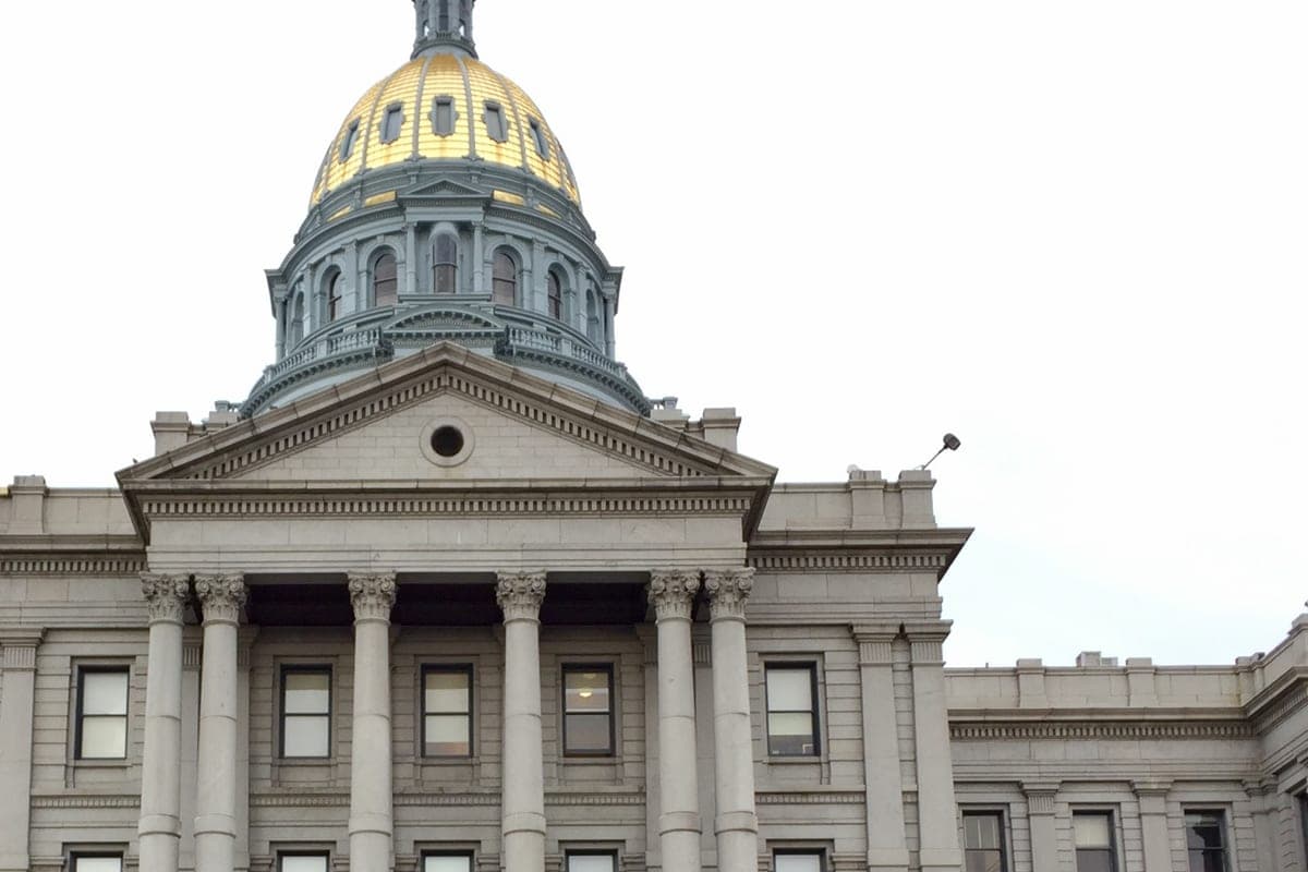 The gold dome and columned front of the Colorado State Capitol in Denver.