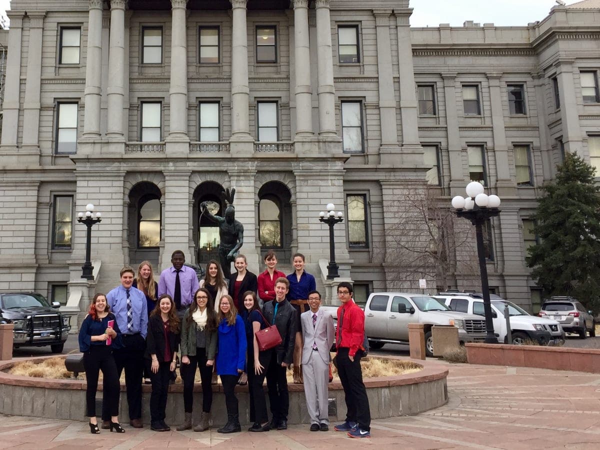 High school students in business dress standing together in front of the Colorado State Capitol.