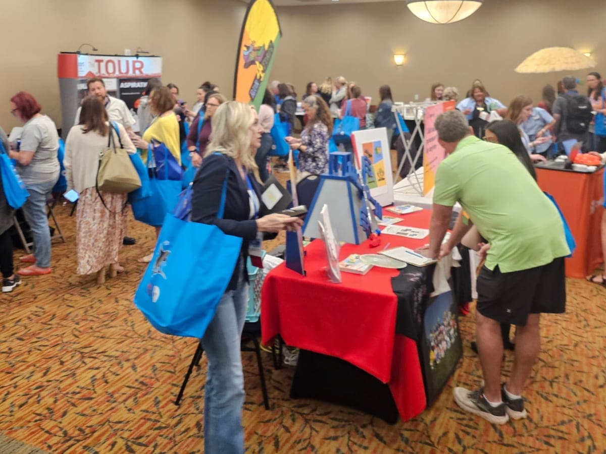Attendees with blue tote bags visiting exhibitor tables at the 2024 Colorado PTA convention.