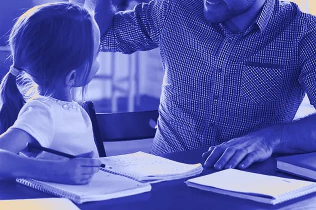 A young girl writing in her notebook at a table looks up at her father, who sits beside her.