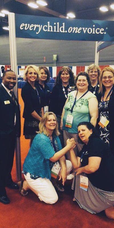 Colorado PTA leaders smiling together at a PTA convention under a banner that reads “every child. one voice.”